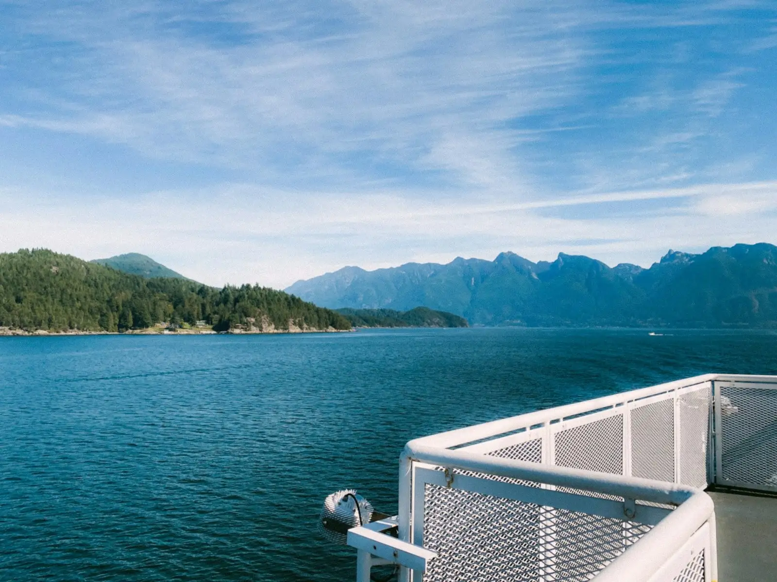 Forested shoreline and coastal mountains seen from a ferry deck on the Sunshine Coast.